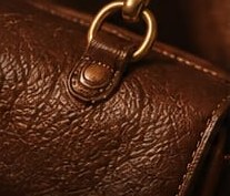 Close-up of a brown leather bag with a brass ring